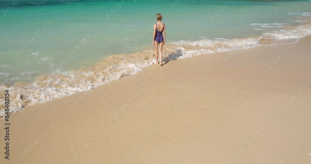 Pretty woman going to swim in tropical blue turquoise ocean water. Wide angle shot. Pretty woman going to swim in tropical blue turquoise ocean water. Wide angle shot.