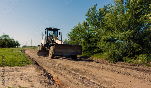 The motor grader improves the road surface and repairs the road.