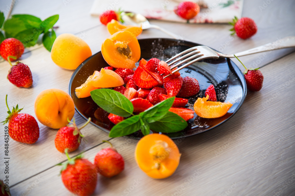 fresh fruit salad of ripe strawberries and apricots, on a light wooden table fresh fruit salad of ripe strawberries and apricots, on a light wooden table