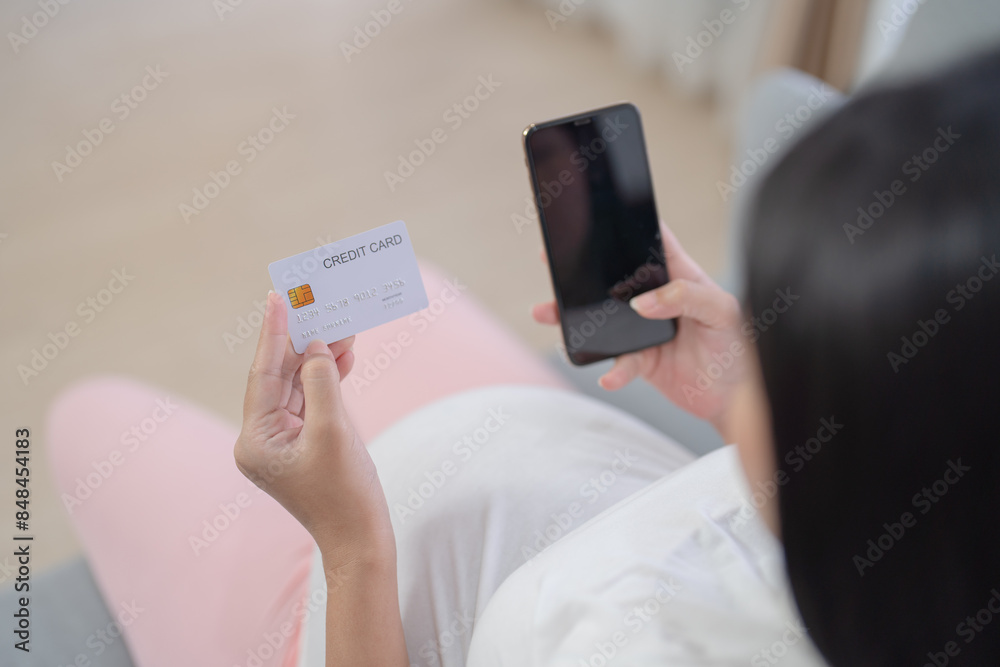 A portrait of happy Asian pregnant woman using a mobile phone device with credit card, shopping online in bedroom at home. Having a baby. Family people lifestyle. Mom love. A portrait of happy Asian pregnant woman using a mobile phone device with credit card, shopping online in bedroom at home. Having a baby. Family people lifestyle. Mom love.