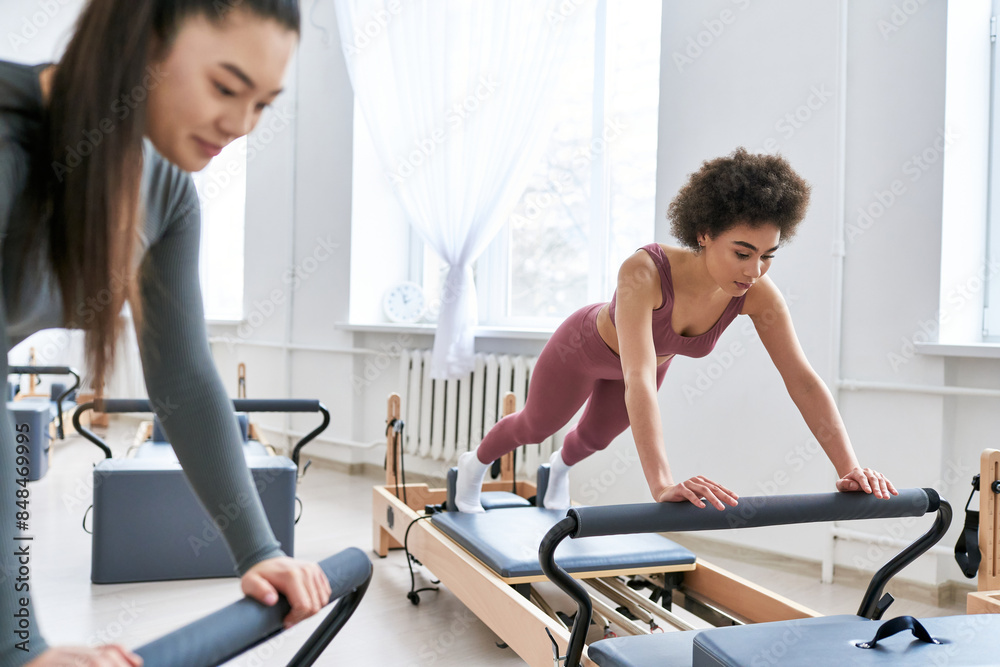 Attractive woman is intensively exercising next to her friend.