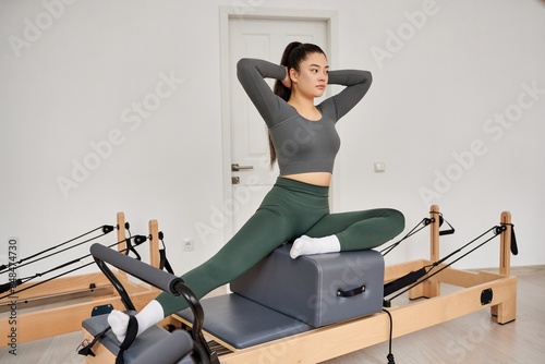 Woman in gray top and green pants works out in gym. photo