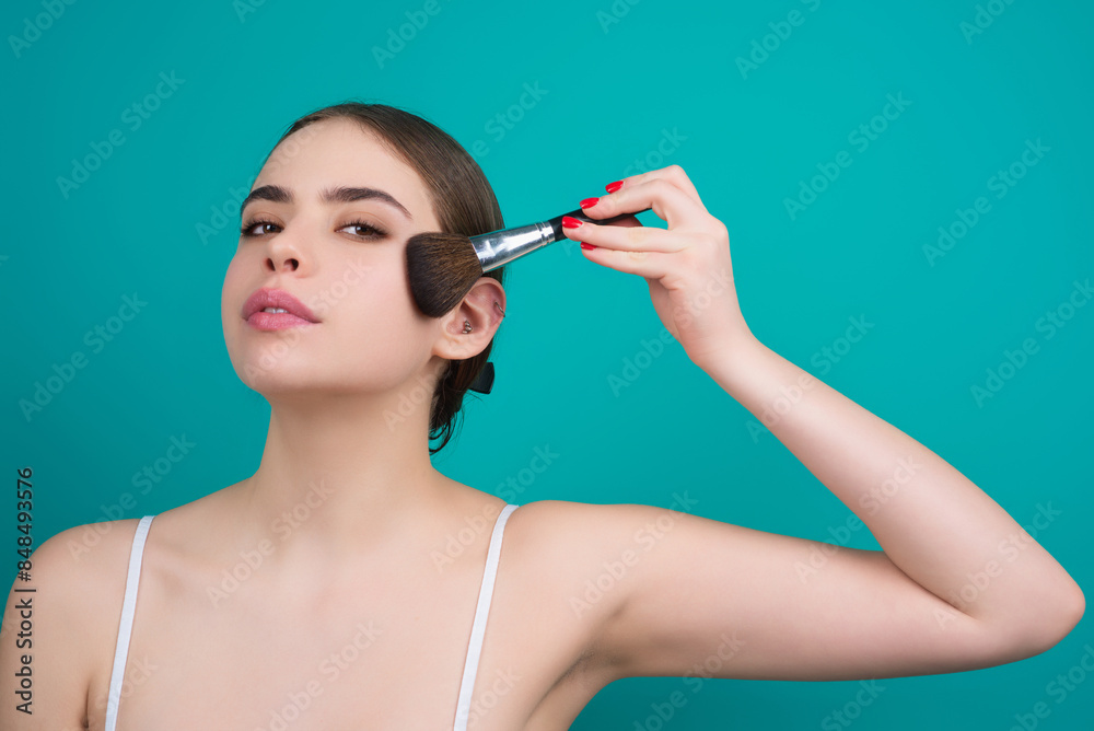 Obraz premium Girl hold blush blusher apply powder visage isolated over studio background. Woman powdering cheeks. Makeup brush. Female model gets blush powder on the cheekbones.