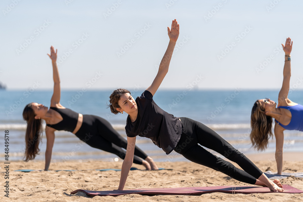 Fototapeta premium Women Practicing Side Plank Pilates on the Beach