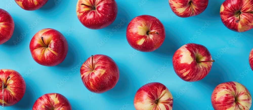 Fresh red apples arranged in a vibrant pattern on a blue background, captured from above. Fresh red apples arranged in a vibrant pattern on a blue background, captured from above.