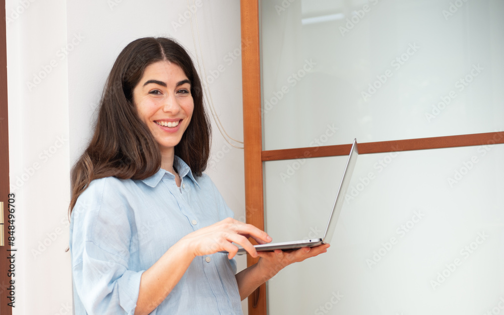 Young woman working from home holding laptop smiling Young woman working from home holding laptop smiling