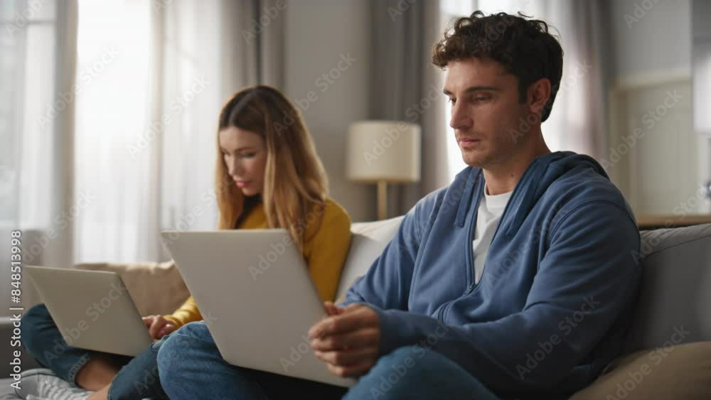 Focused spouses working computers couch together closeup. Young pair freelancers Focused spouses working computers couch together closeup. Young pair freelancers
