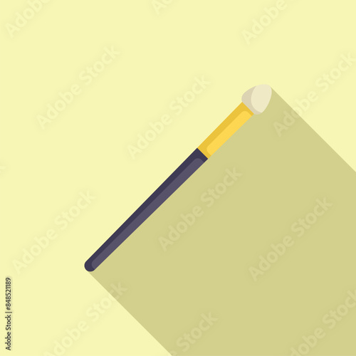 Makeup brush is laying on a light yellow background, casting a long shadow