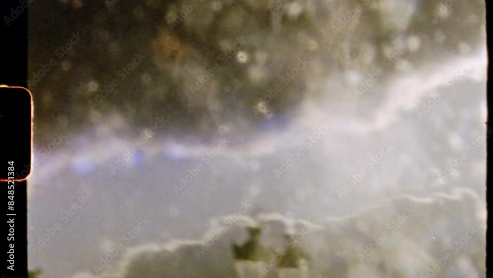 super 8mm vintage film a white fluffy cloud under blue sky. a view from through beautiful sunny 