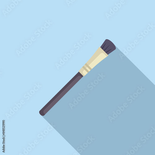 Makeup brush is lying diagonally on a blue background, casting a long shadow