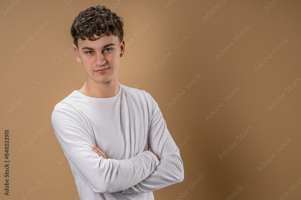 Portrait of one caucasian man 20 years old looking to the camera in front of almond color studio background wearing casual shirt copy space Portrait of one caucasian man 20 years old looking to the camera in front of almond color studio background wearing casual shirt copy space