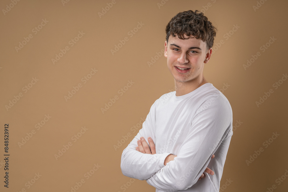 Portrait of one caucasian man 20 years old looking to the camera in front of almond color studio background smiling wearing casual shirt copy space Portrait of one caucasian man 20 years old looking to the camera in front of almond color studio background smiling wearing casual shirt copy space