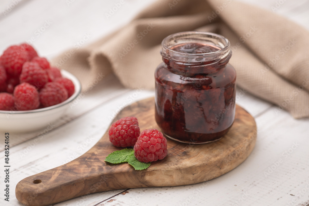 Homemade berry jam. Jar of raspberry jam and a bowl of fresh berries on a white wooden table. Homemade berry jam. Jar of raspberry jam and a bowl of fresh berries on a white wooden table.