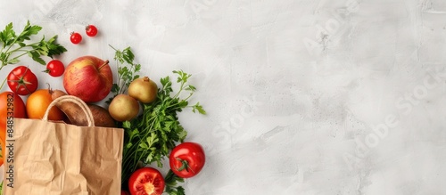 Fresh fruits and vegetables in a Kraft bag against a light background, sourced from the farmers' market. Room for text.