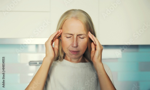 Tired mature woman with headache, stress, fatigue, temples pain, suffers from migraine at home