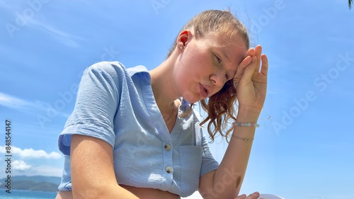 Young woman feeling bad, suffering from sunstroke at sea, beach at summer