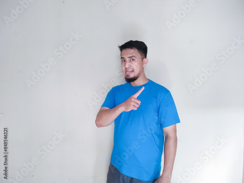 Asian man wearing blue t-shirt pointing to left side photo