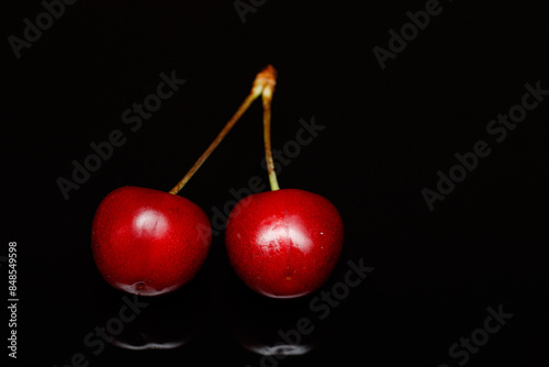 Red cherries on an abstract black background are small, juicy fruits of a bright red hue. With a sweet taste, they are a summertime favorite.