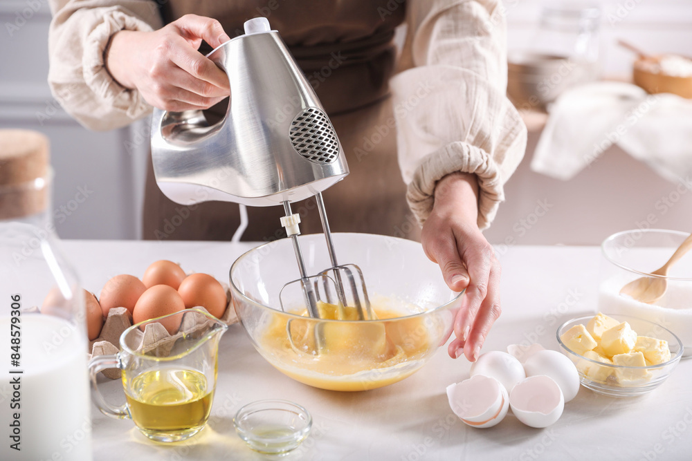 Woman making dough with mixer in bowl at table, closeup Woman making dough with mixer in bowl at table, closeup