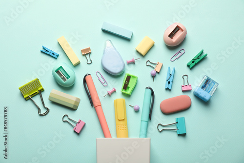 Flat lay composition with holder and different stationery on turquoise background