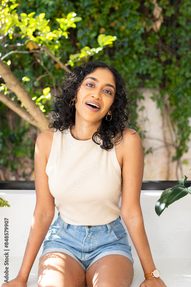Young Asian woman sitting outdoors, smiling brightly Young Asian woman sitting outdoors, smiling brightly