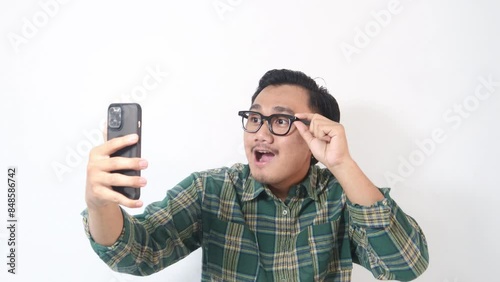 Footage of adult Asian man looking to his handphone with surprised expression. photo