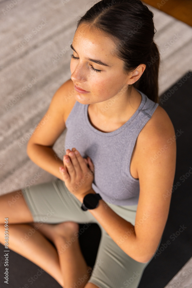 Young Caucasian woman meditating with hands in prayer position on yoga mat Young Caucasian woman meditating with hands in prayer position on yoga mat