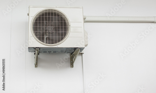 The external air conditioner is installed on a white wall except for copy space.