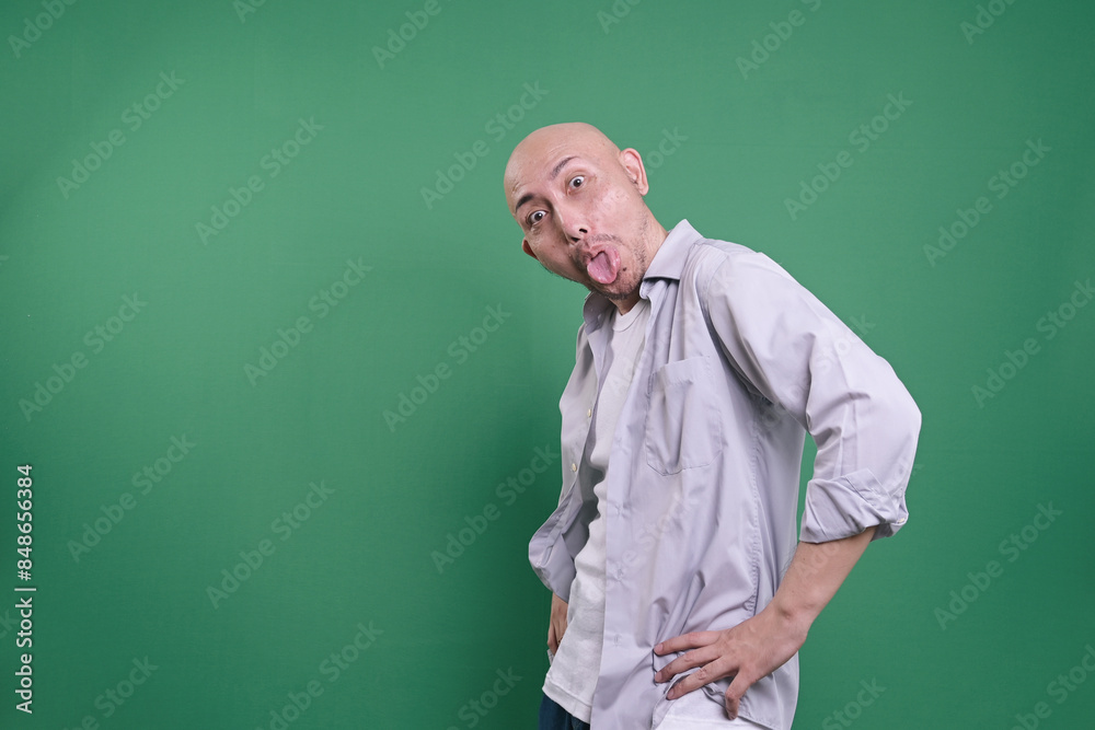 Funny Bald Man Mocking With Funny Face, Sticking Out His Tongue With Hand On Waist Funny Bald Man Mocking With Funny Face, Sticking Out His Tongue With Hand On Waist