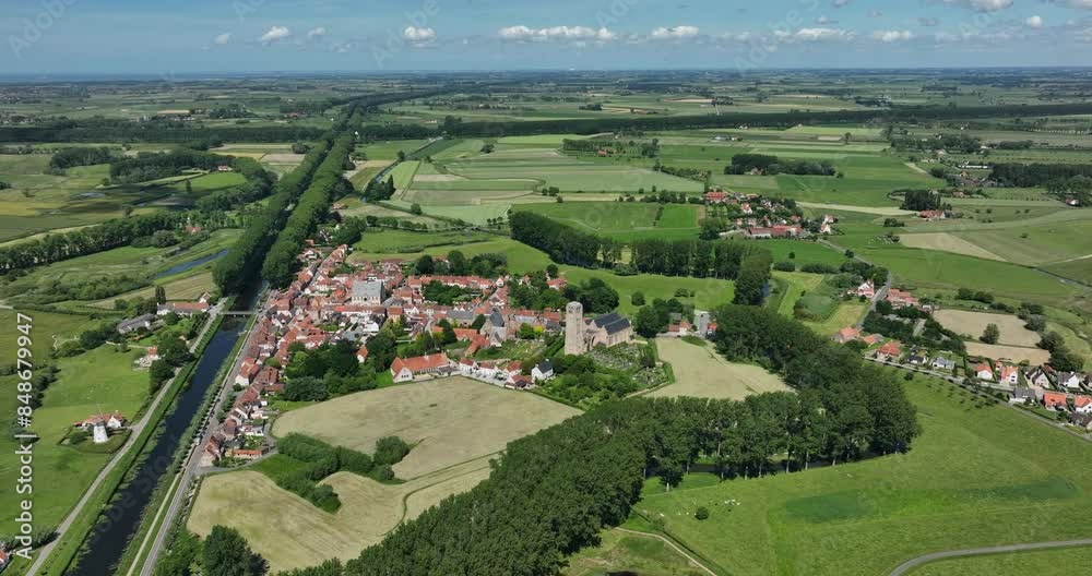 Damme, Belgium, June 2022. Drone orbits while slowly descending towards the village with Our Lady Ascension Church and Stadhuis Damme surrounded by countryside with farmlands on a sunny day. Damme, Belgium, June 2022. Drone orbits while slowly descending towards the village with Our Lady Ascension Church and Stadhuis Damme surrounded by countryside with farmlands on a sunny day.