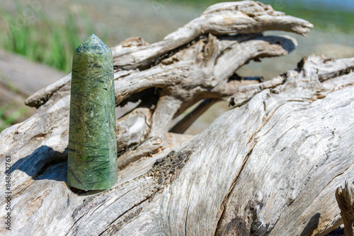 A close up image of a epidote crystal tower with tourmaline inclusions on a driftwood log.  photo