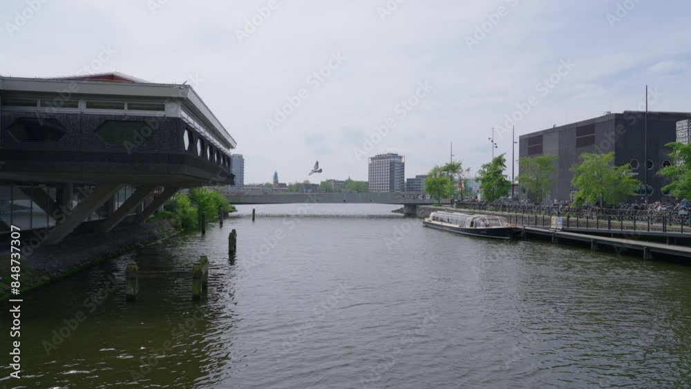 A wide shot of a canal with modern buildings looking toward the IJ river and south Amsterdam, on a sunny spring day A wide shot of a canal with modern buildings looking toward the IJ river and south Amsterdam, on a sunny spring day
