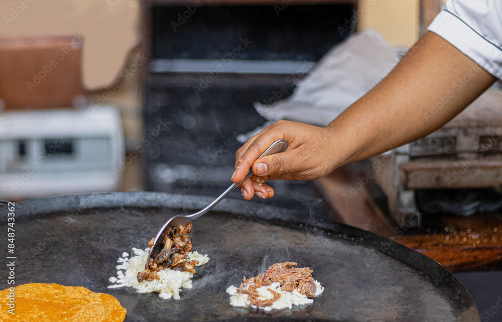 Obraz premium woman's hand cooking mexican food, heating tortillas and preparing carnitas y quesadillas