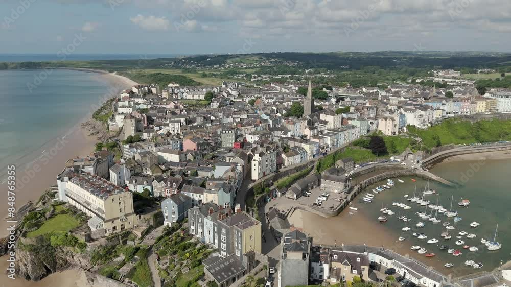 An aerial view of the of the Welsh harbour town of Tenby in Pembrokeshire, South Wales, on a sunny summer morning. Flying left to right while circling the town centre. An aerial view of the of the Welsh harbour town of Tenby in Pembrokeshire, South Wales, on a sunny summer morning. Flying left to right while circling the town centre.