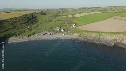 An aerial view of Abereiddi beach in Pembrokeshire, South Wales, on a sunny evening with a clear blue sky. Flying right ro left over the sea while elevating and panning down onto the beach. photo