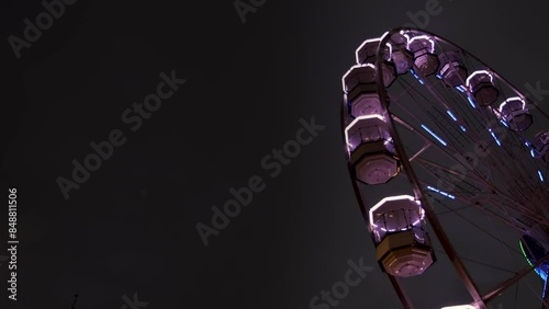 Footage of a ferris wheel in the evenening taken in the city centre of Leeds in West Yorkshire in the UK showing the colourful lights on the fun fair in the night time photo