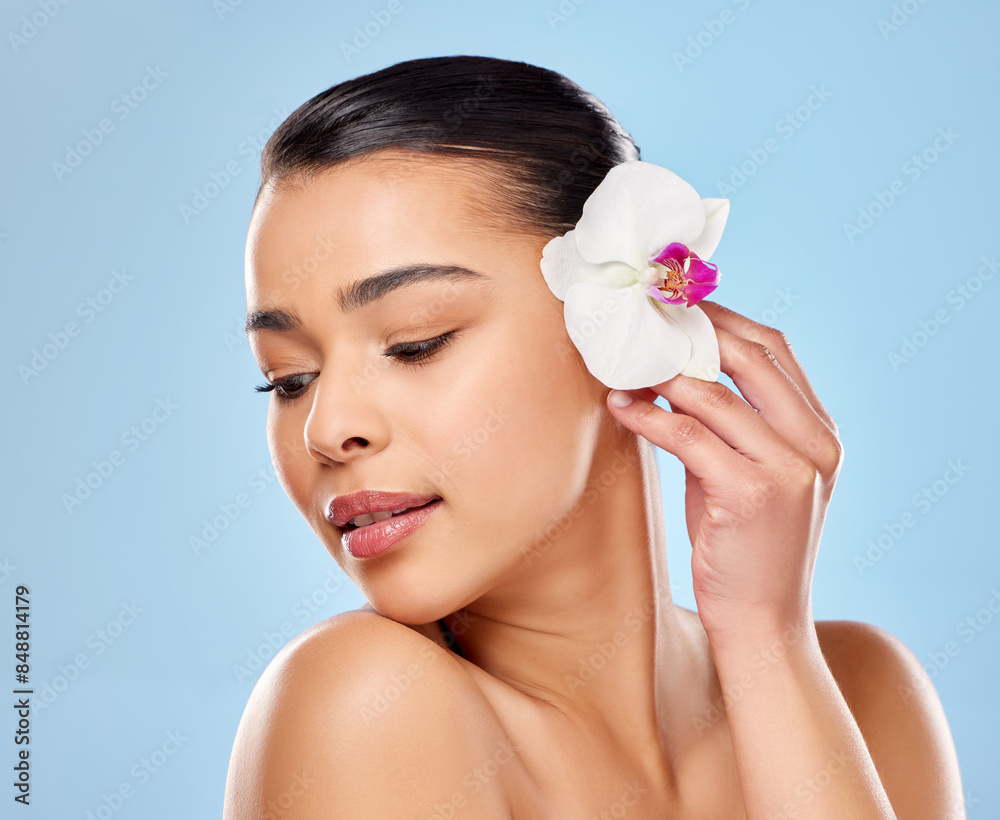 Woman, flower and beauty in studio or smooth skin, soft and sustainable cosmetics on blue background. Female person, orchid plant and organic facial treatment, dermatology and eco friendly makeup Woman, flower and beauty in studio or smooth skin, soft and sustainable cosmetics on blue background. Female person, orchid plant and organic facial treatment, dermatology and eco friendly makeup