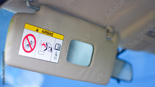 Airbag warning sign with mirror inside a car, located above the cabin