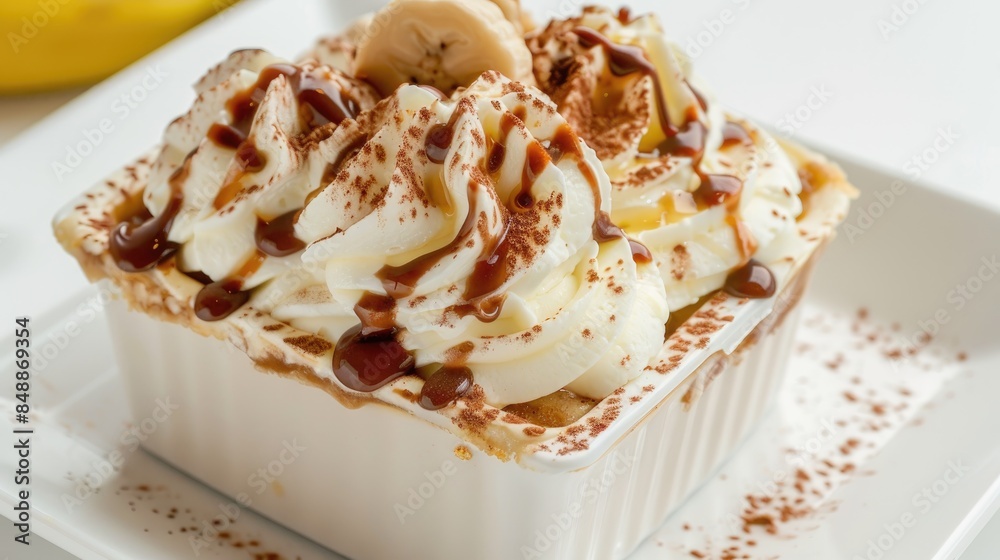 Banoffee pie presented in a square cup on a white backdrop Banoffee pie presented in a square cup on a white backdrop