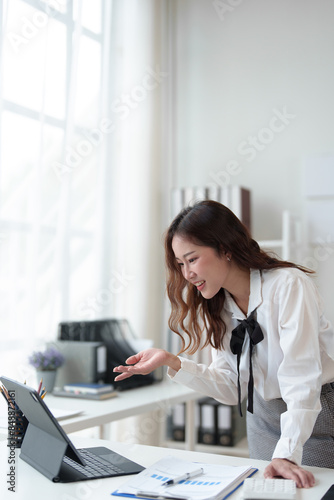 Happy Asian businesswoman in office working on financial documents, checking, validating data on laptop, results, income, online marketing. Company taxes Online business work.