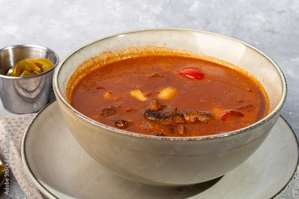 Tom yum soup with seafood, capers added nearby.