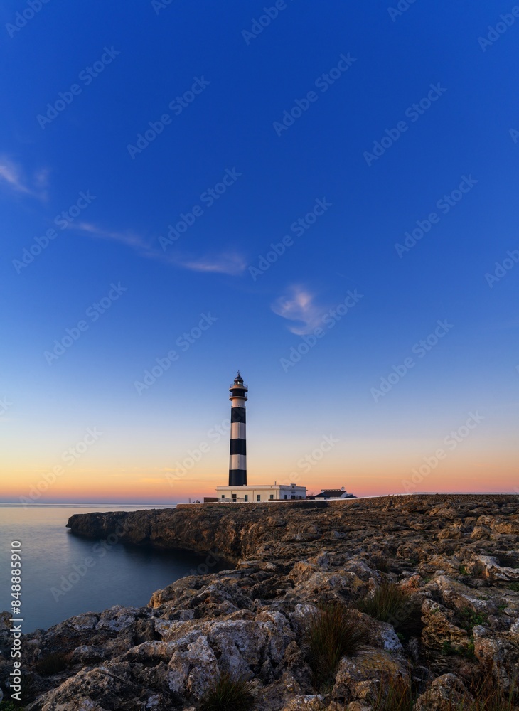 vertical view of the landmark Cap d'Artrutx lighthouse on Menorca Island just after sunrise vertical view of the landmark Cap d'Artrutx lighthouse on Menorca Island just after sunrise