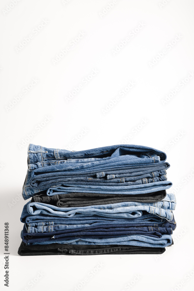 A beautiful stack of folded denim jeans in different shades of blue and black. Denim background A beautiful stack of folded denim jeans in different shades of blue and black. Denim background