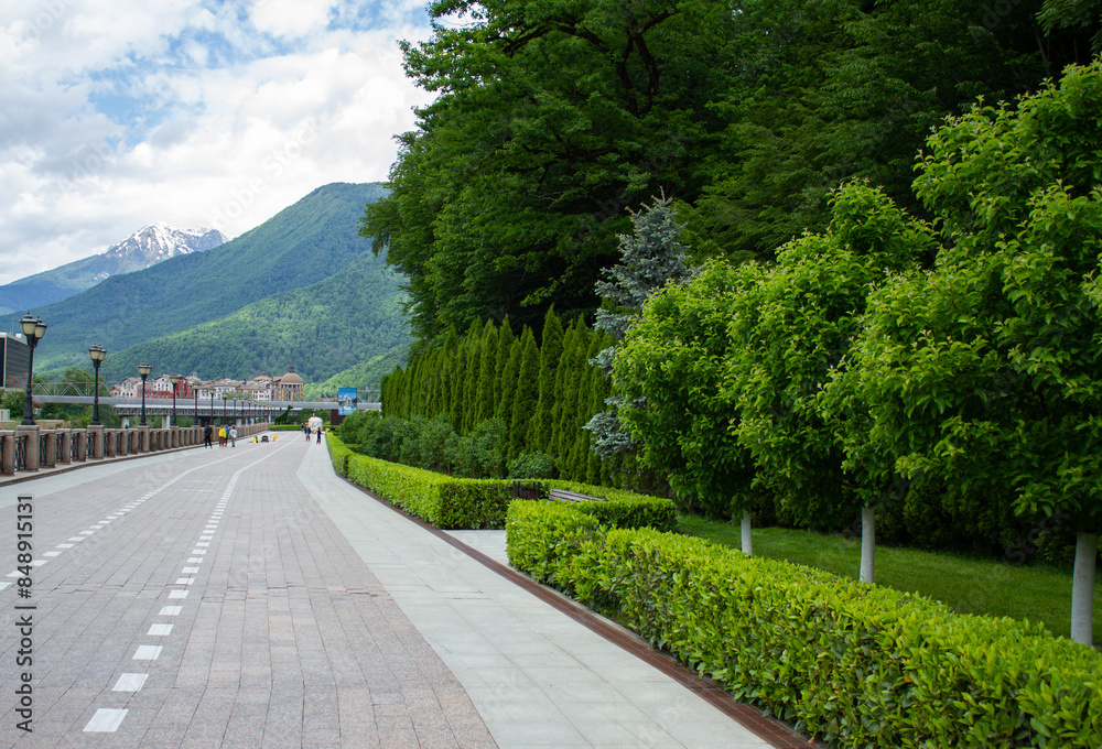 Fototapeta premium Rosa Khutor embankment, mountains and green forest. Krasnaya Polyana, Sochi.