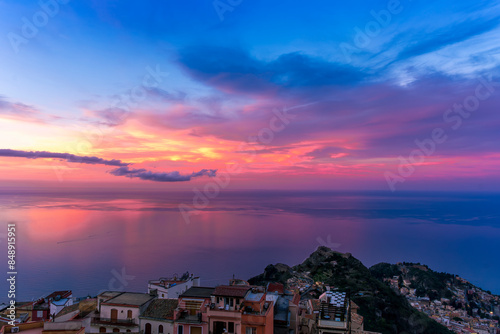 sceniv view from a high mountain town to amazing landscape of sea coast, roofs in vintage style of Italy and beautiful colorful sunset or sunrise cloudy sky