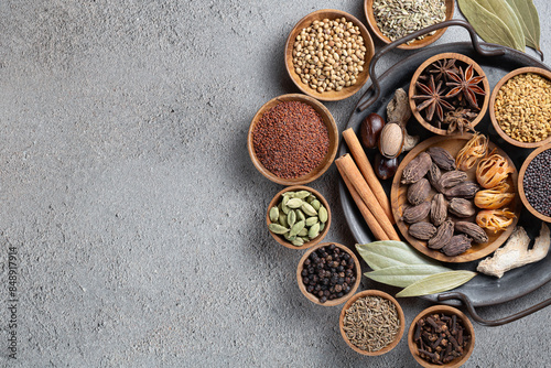 Fototapeta Naklejka Na Ścianę i Meble -  A variety of whole textured Indian spices in wooden bowls on a gray background with copyspace top view