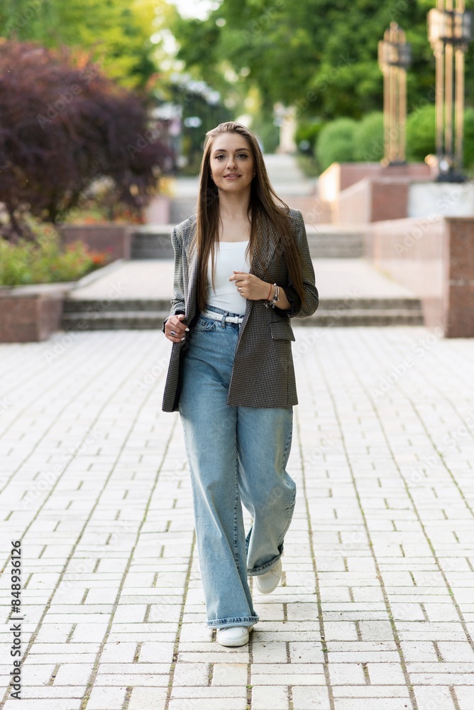 Pretty and attractive Caucasian young woman in stylish casual clothes posing with pleasure while walking in the park on a warm spring day. The concept of freedom, relax, style. Pretty and attractive Caucasian young woman in stylish casual clothes posing with pleasure while walking in the park on a warm spring day. The concept of freedom, relax, style.