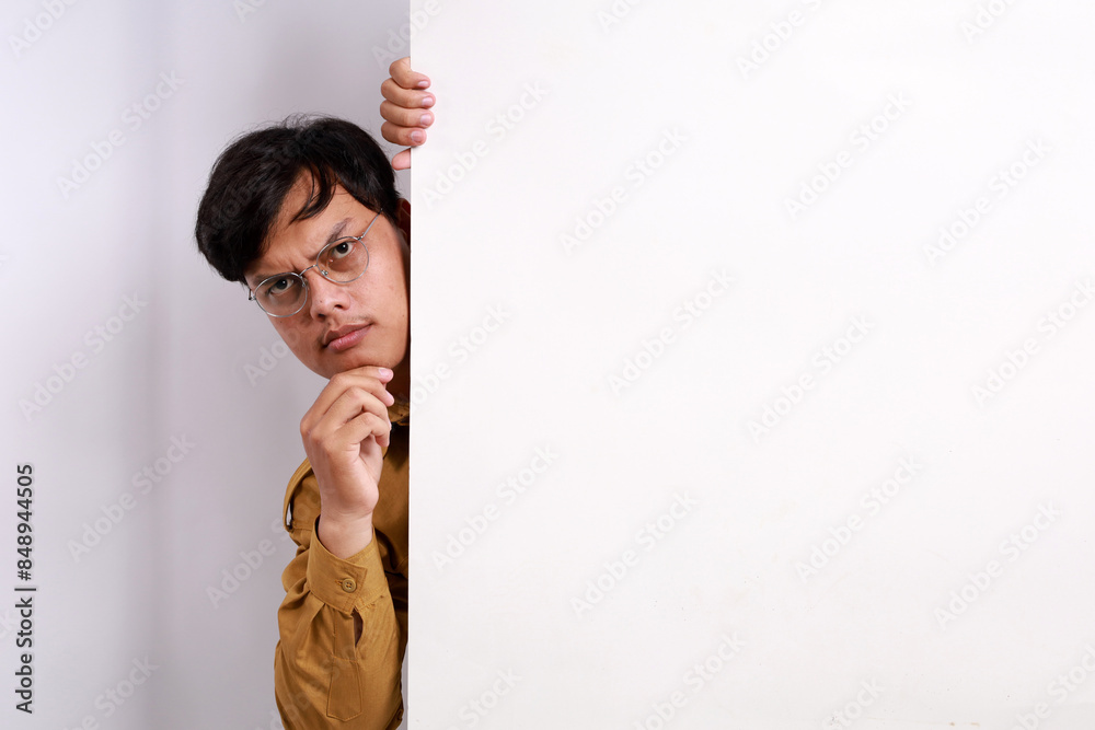 Curious Indonesian civil servant man peeking behind the wall Curious Indonesian civil servant man peeking behind the wall
