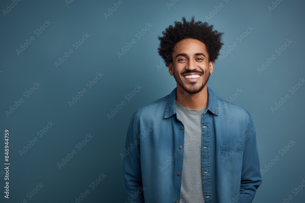 Portrait of a glad afro-american man in his 20s sporting a versatile denim shirt isolated in minimalist or empty room background Portrait of a glad afro-american man in his 20s sporting a versatile denim shirt isolated in minimalist or empty room background