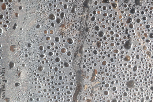 A closeup photograph capturing water droplets on a metallic surface, forming an abstract pattern